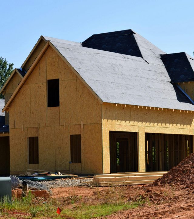 A partially built wooden house under construction, showcasing its progress and design in daylight.